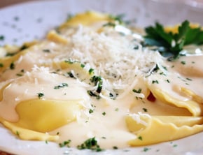 ravioli topped with white, creamy sauce