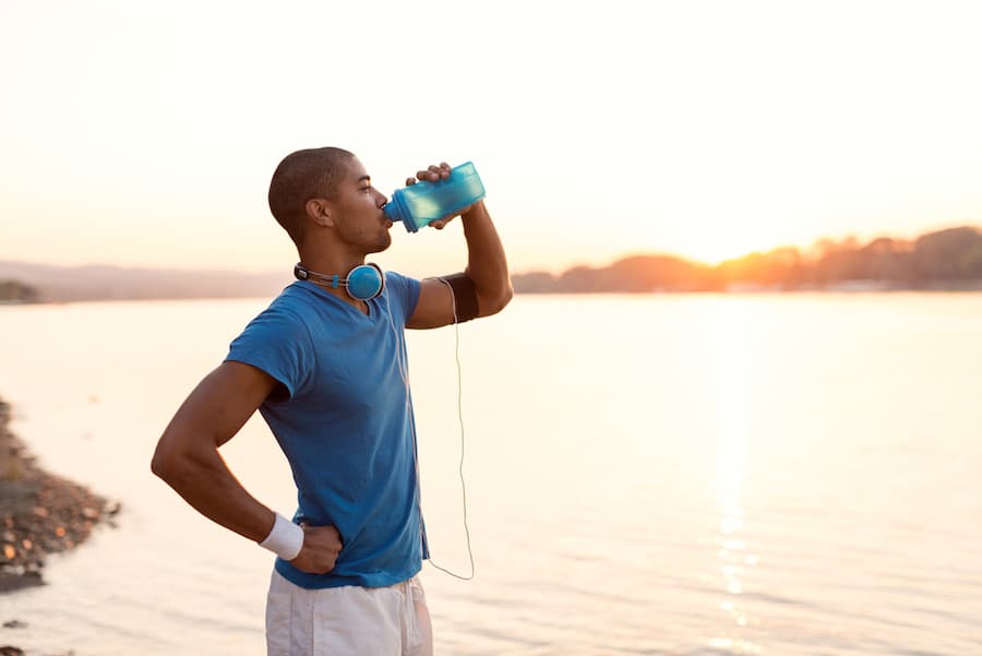 person drinking protein beverage in front of lake